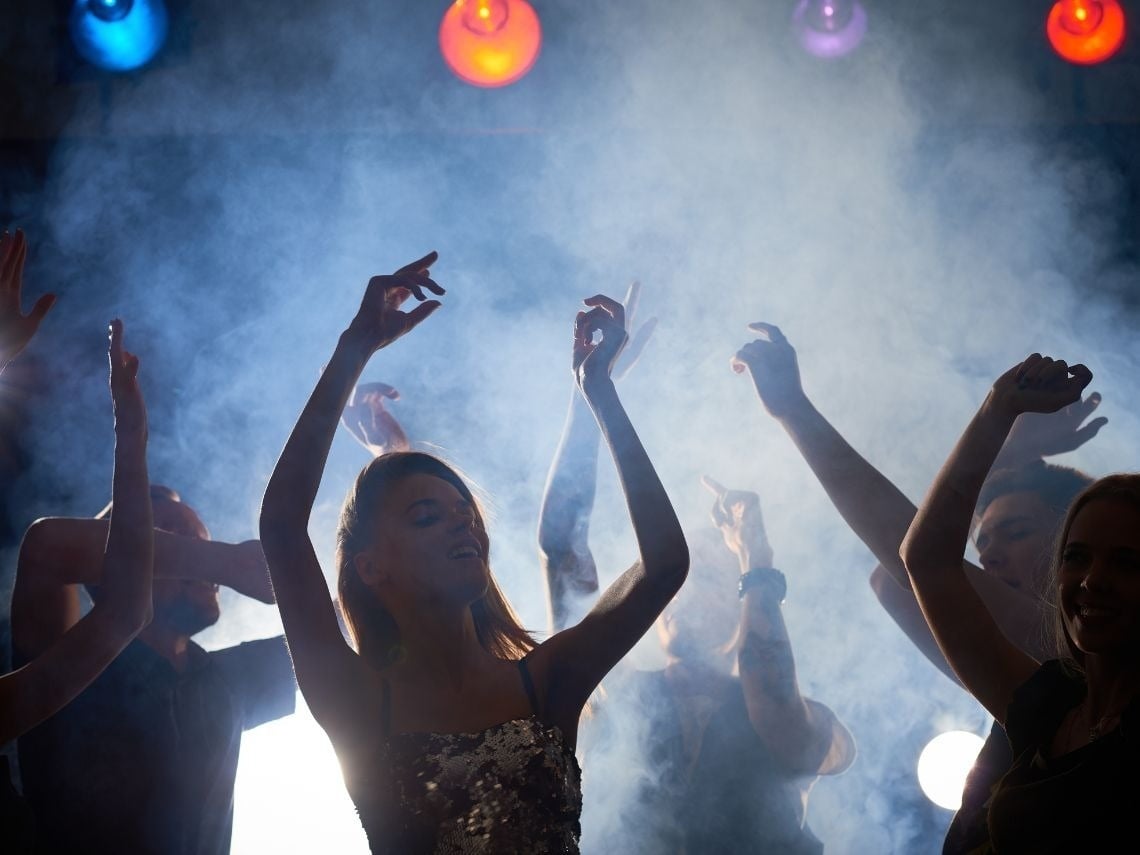 Gente bailando y disfrutando en discoteca con luces y humo. Ideal para eventos corporativos Tequendama.