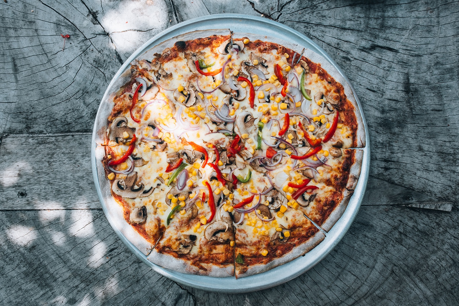 Tequendama Corporativa: Delicious pizza with mushrooms, corn, and peppers on rustic wood.