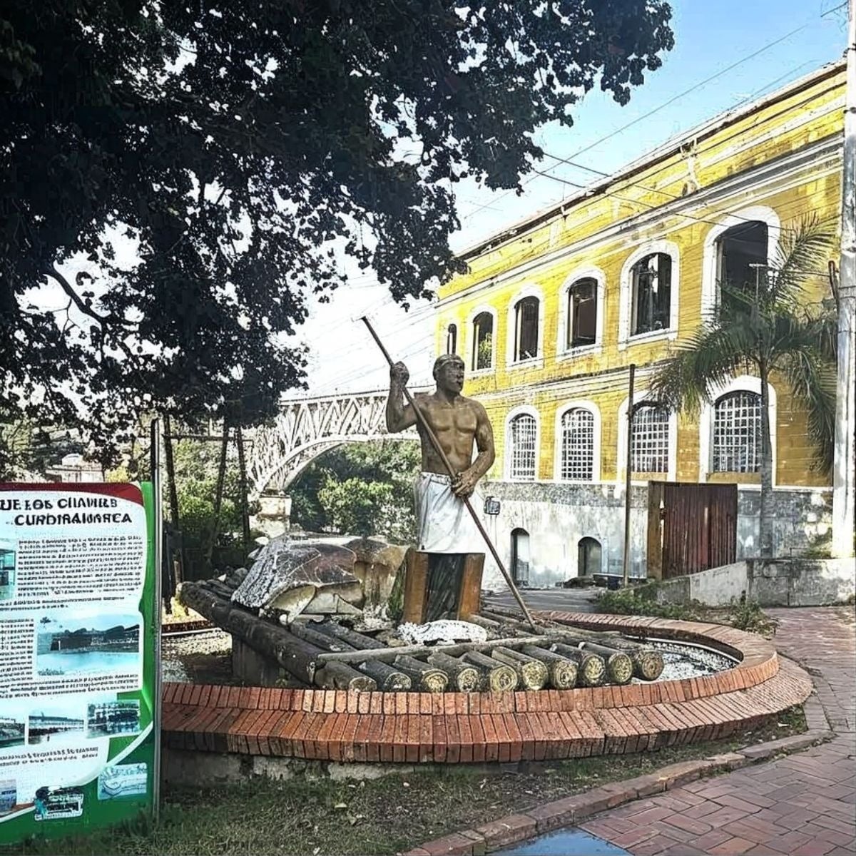 Monumento Tequendama: Corporativa. Estatua de hombre con lanza sobre balsa, edificio amarillo y puente.