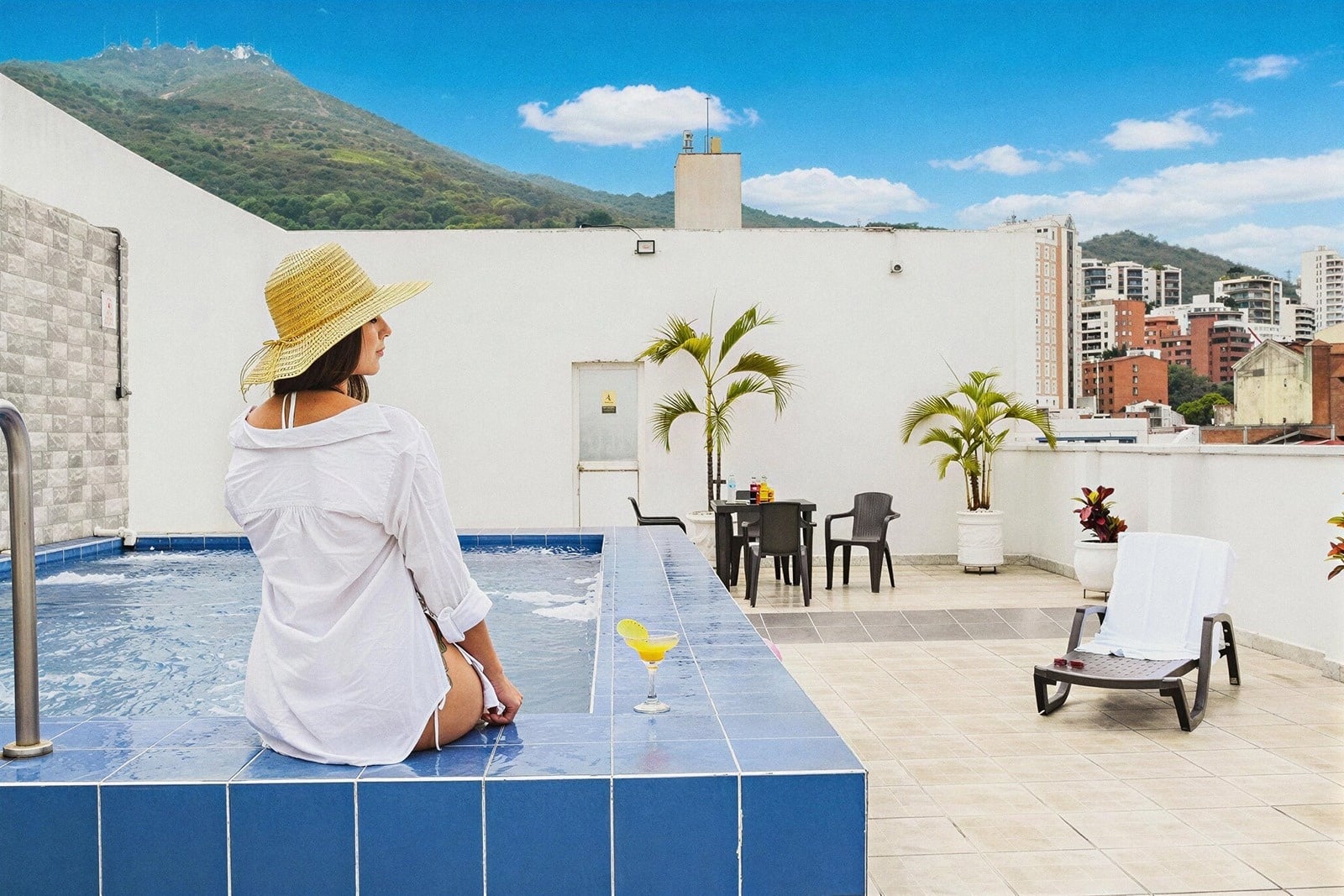 Woman in hat by pool at Tequendama: Corporativa, with city view.