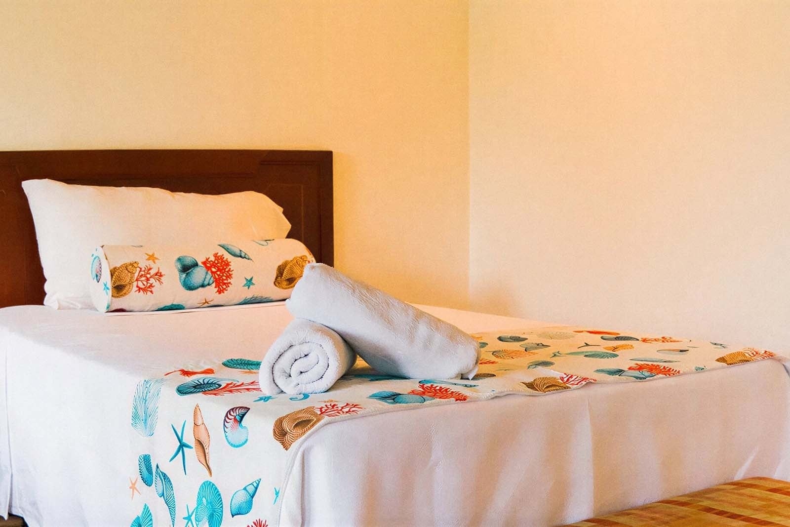 Hotel Rosario de Mar: Bed with nautical decor and towels.
