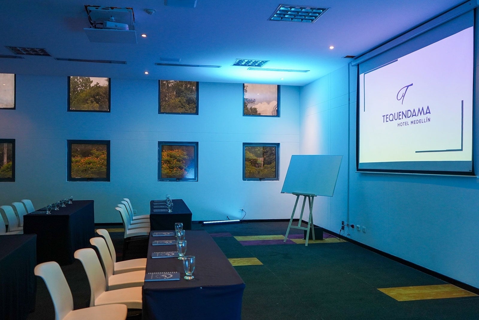 Tequendama Corporate meeting room: set tables and chairs, whiteboard, and screen.