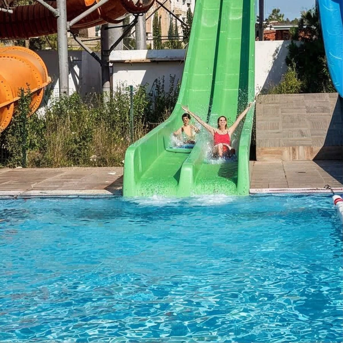 Tequendama: Diversión acuática con niños en tobogán verde, ideal para vacaciones familiares.