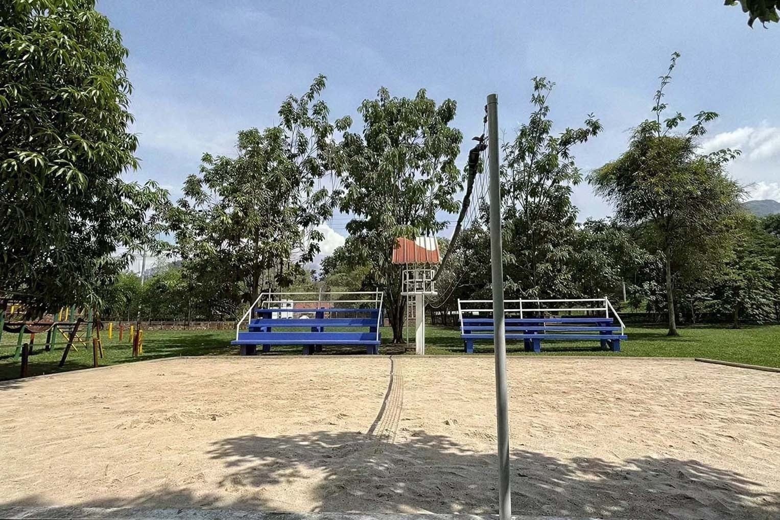 Tequendama: Corporativa volleyball court with blue bleachers and palm trees.