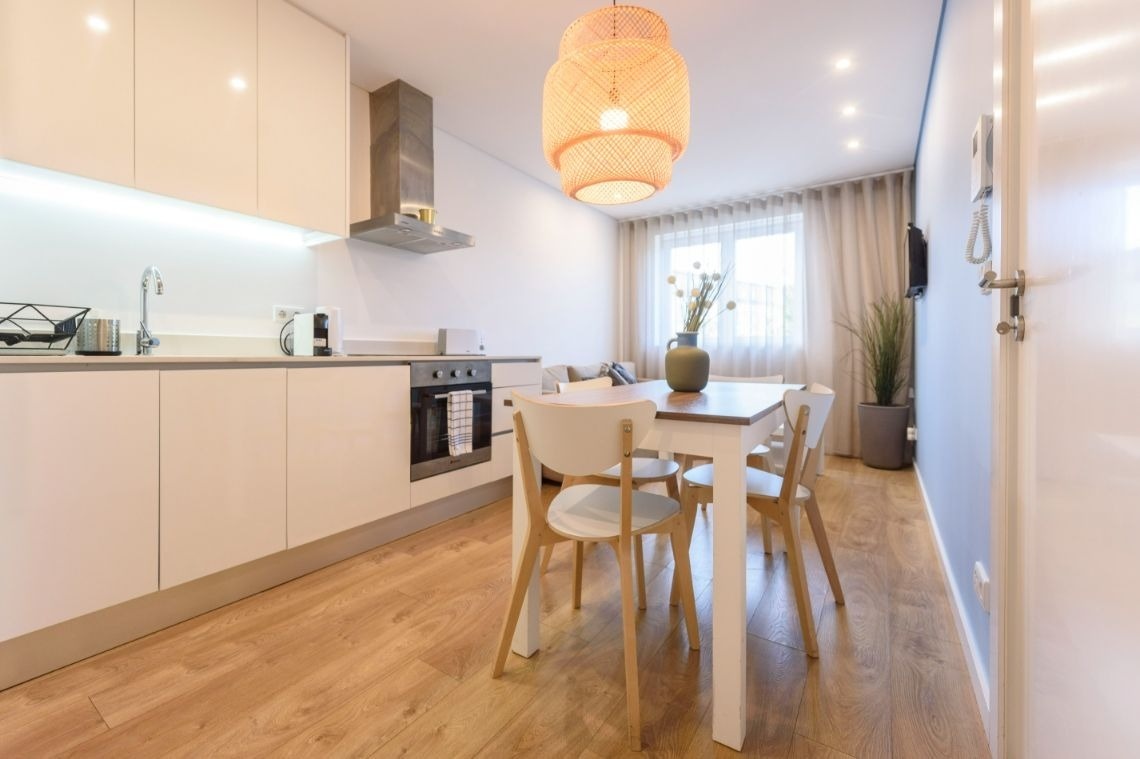 uma cozinha com mesa e cadeiras e um vaso de flores na mesa