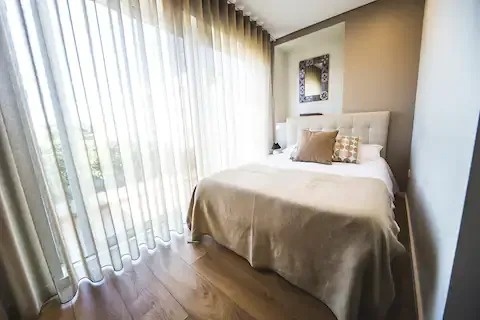 um quarto com cama , cortinas e uma grande janela .