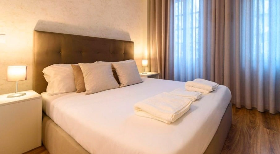 a bed with white sheets and pillows in a hotel room