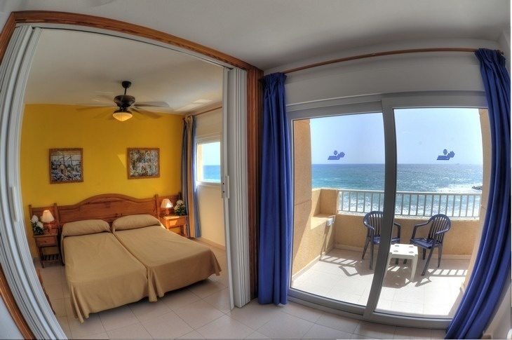 a bedroom with two beds and a balcony overlooking the ocean