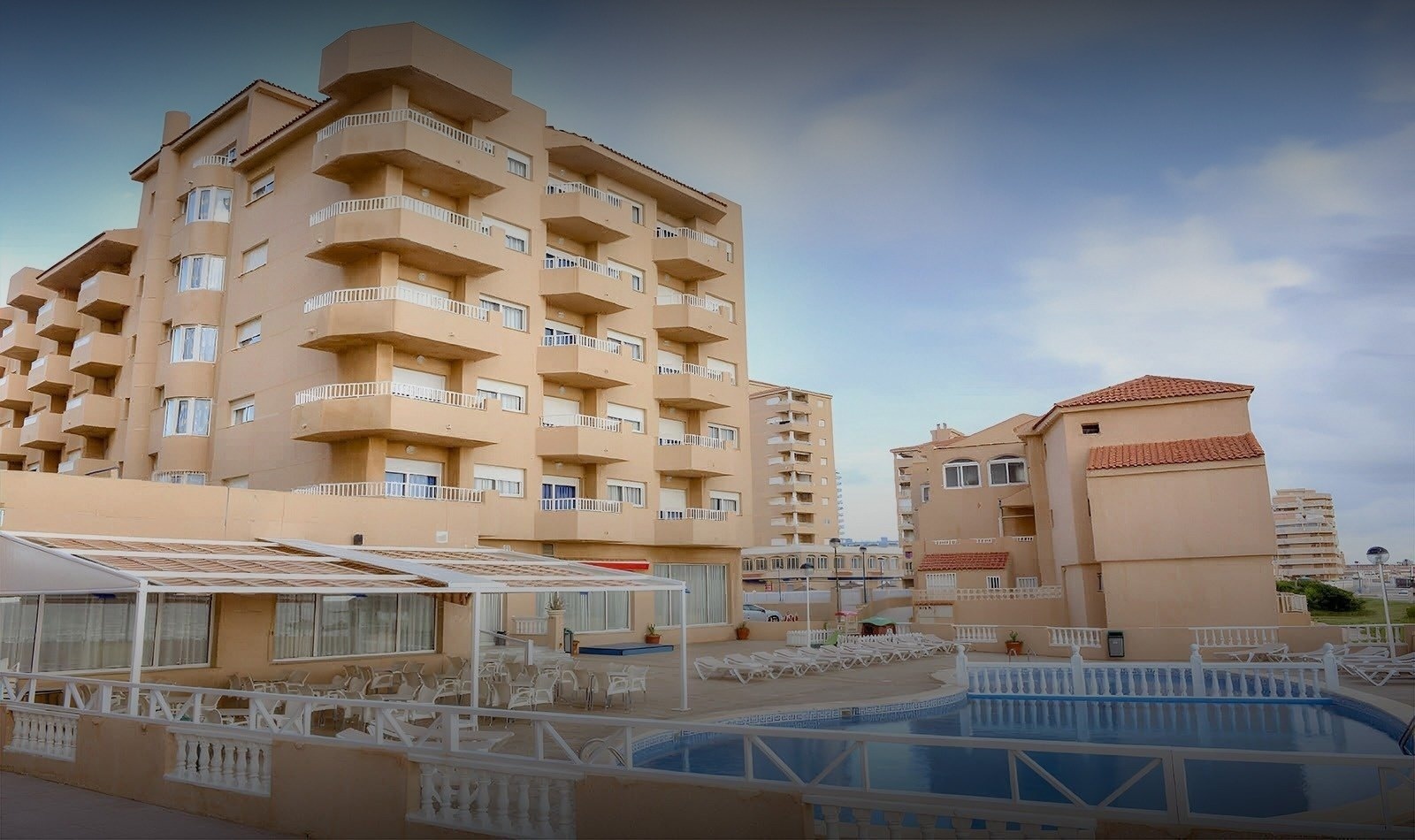 un edificio de apartamentos con una piscina al fondo