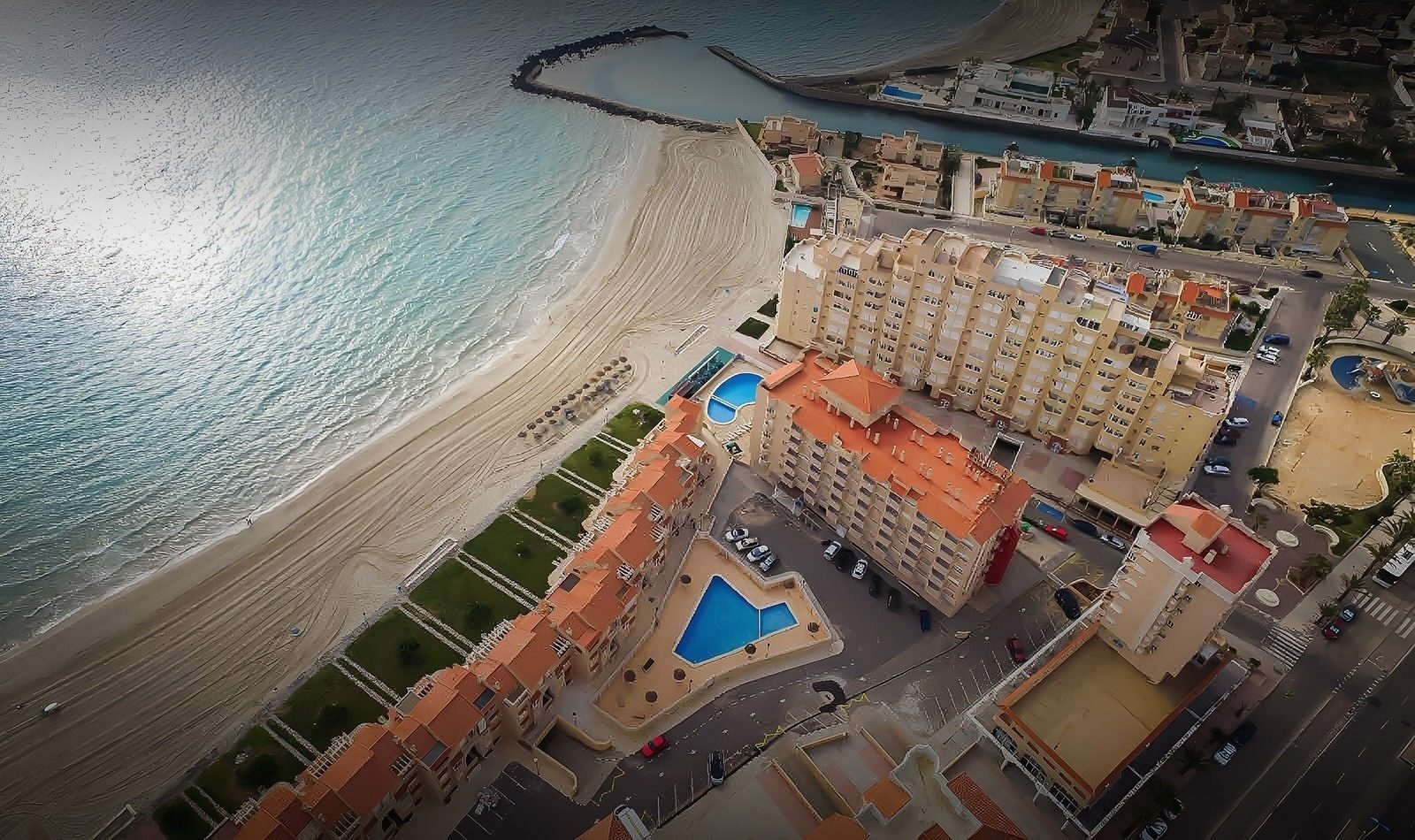 an aerial view of a beach with buildings and a pool