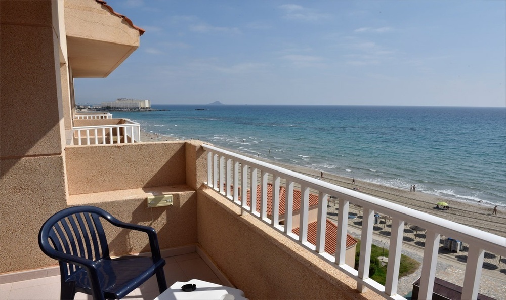 a view of the ocean from a balcony with a blue chair
