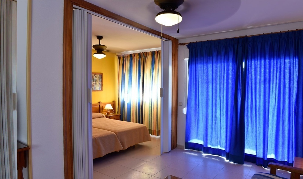 a bedroom with blue curtains and a ceiling fan