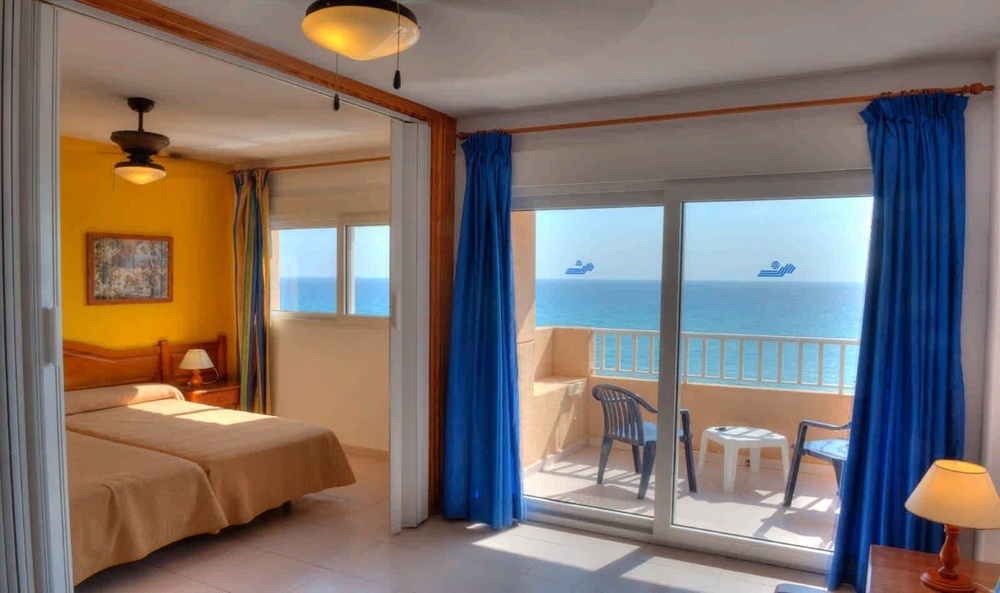 a bedroom with two beds and a balcony overlooking the ocean