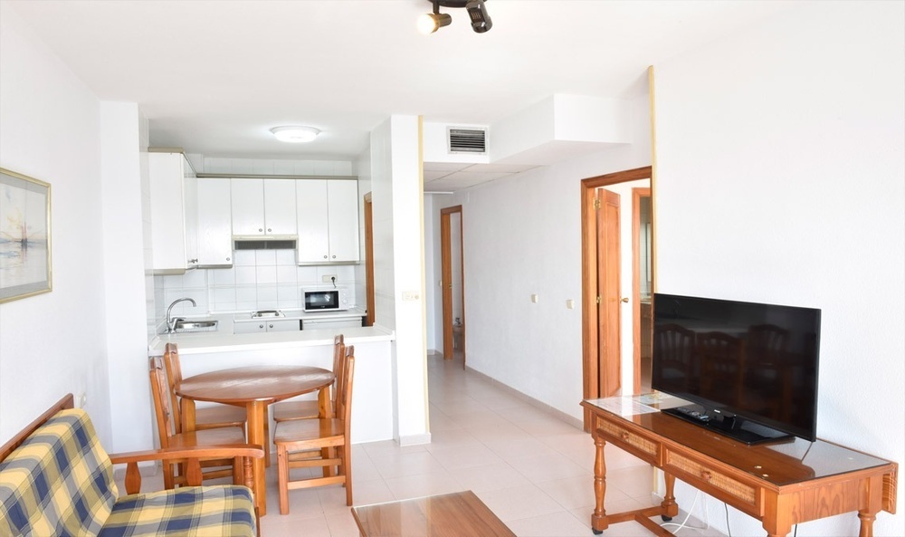 una sala de estar con una televisión y una cocina al fondo