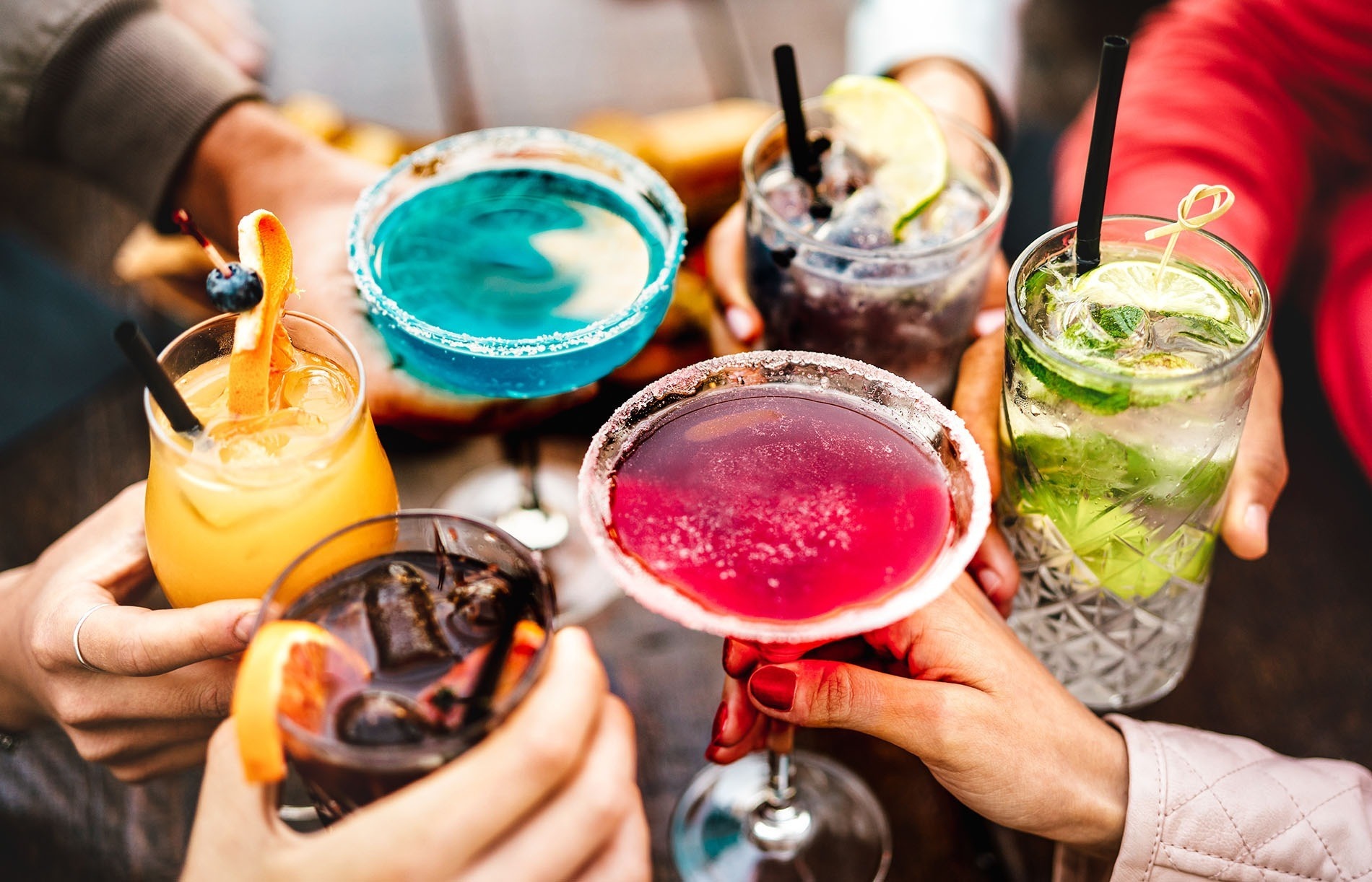 a group of people toasting with different colored drinks