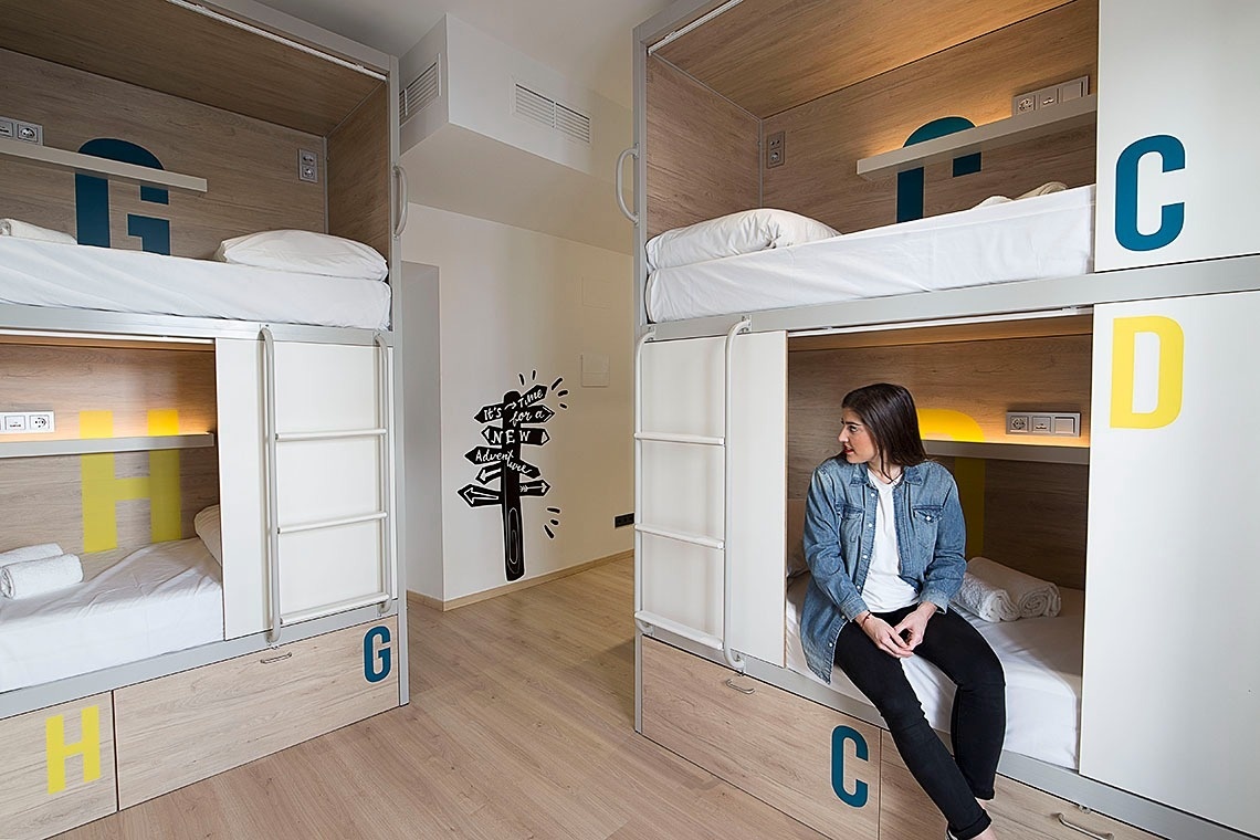 a woman sits on a bunk bed with the letter c on the wall