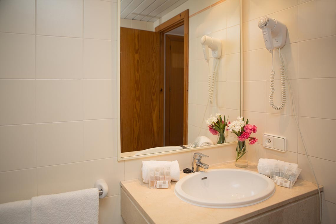 Salle de bain moderne avec sèche-cheveux mural et fleurs fraîches à Gavimar La Mirada | Cala d'Or, Îles Baléares