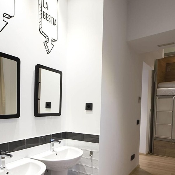un baño con dos lavabos y dos espejos con la bestia escrito en la pared
