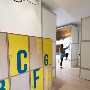 a woman is standing in a hallway with lockers that have the letters a b c and g on them
