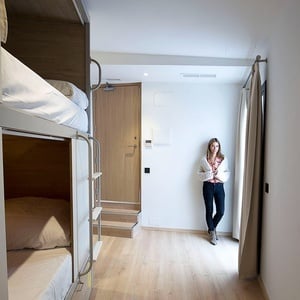 una mujer se para en una habitación con literas y una puerta