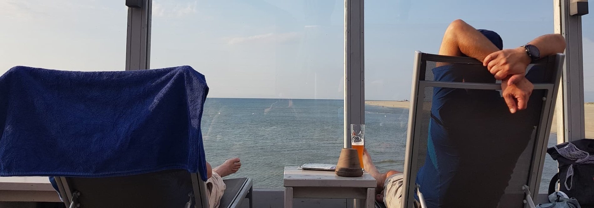 a man sits in a chair looking out a window at the ocean