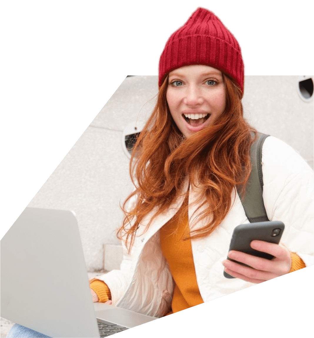 una mujer con un sombrero rojo sostiene un teléfono y una computadora portátil