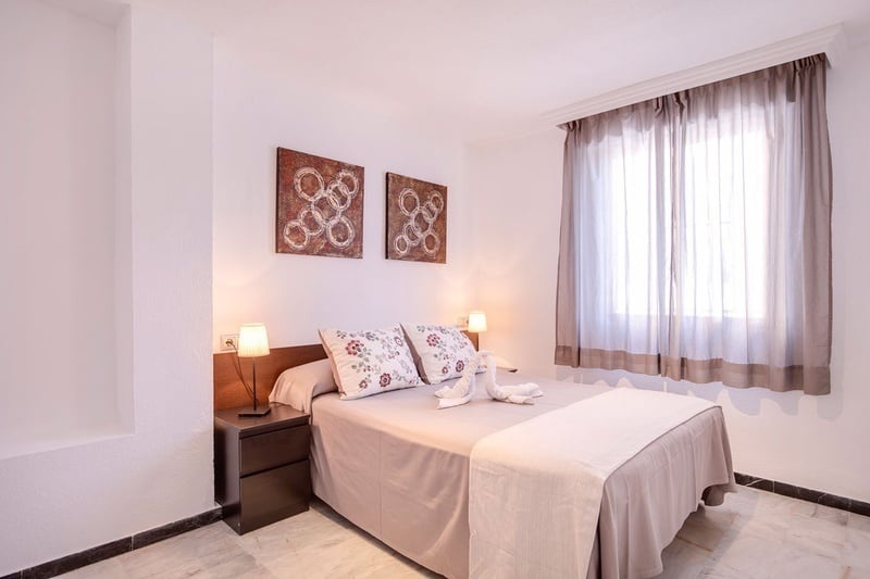  Dormitorio acogedor con cama doble, lámparas de noche y cuadros decorativos.