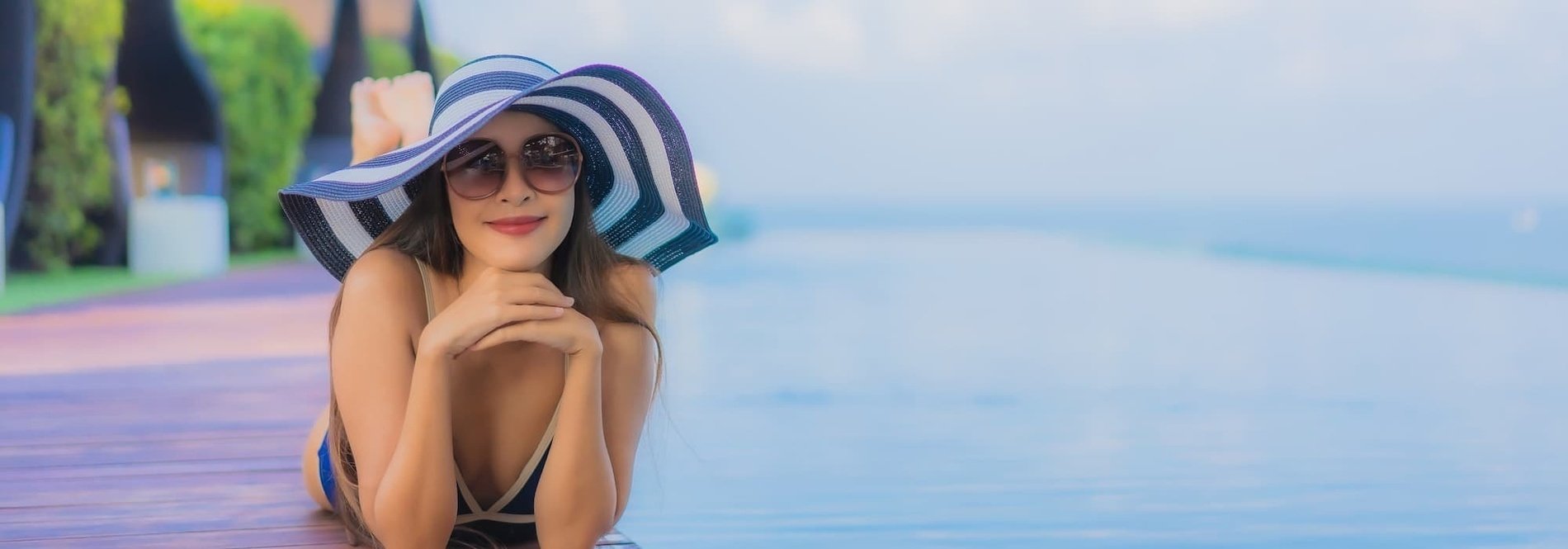 a woman wearing a hat and sunglasses is laying on a wooden deck