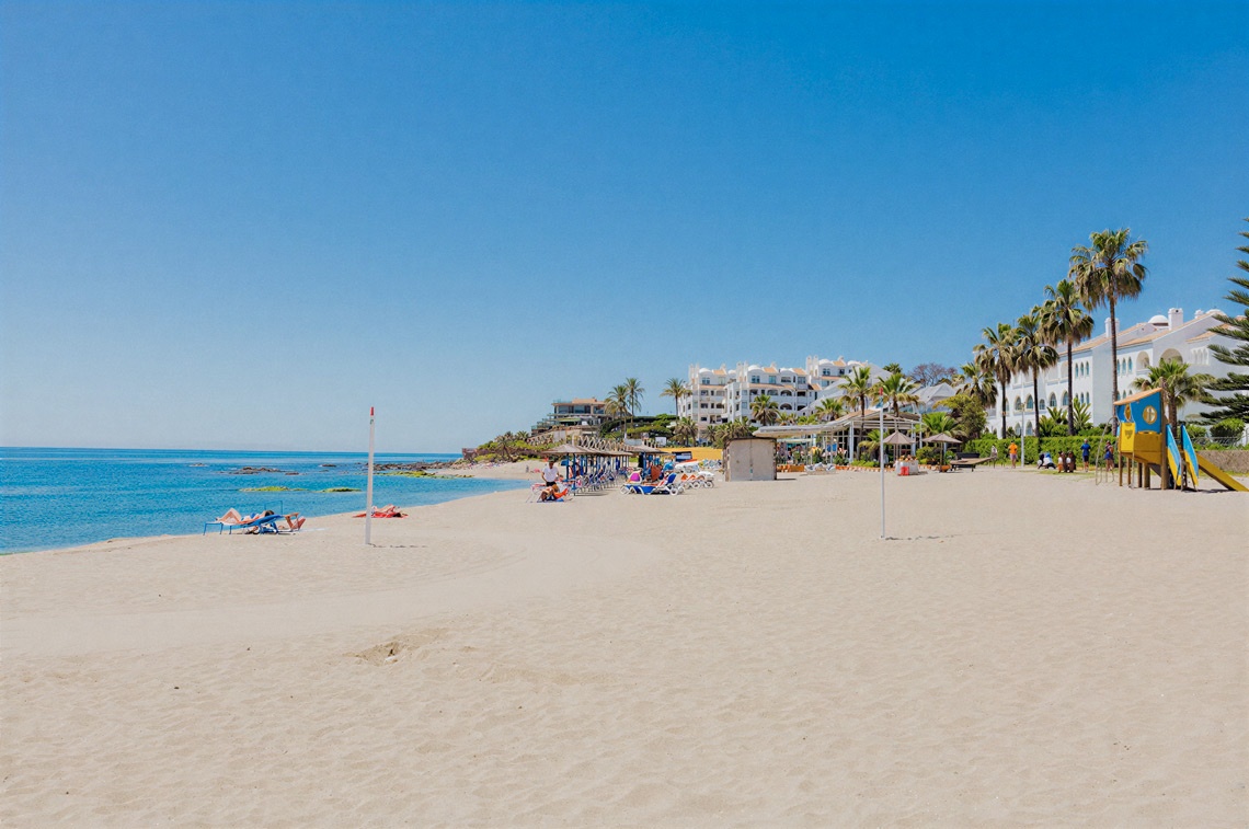 Beach with holiday hotels, sunbeds and blue sea.