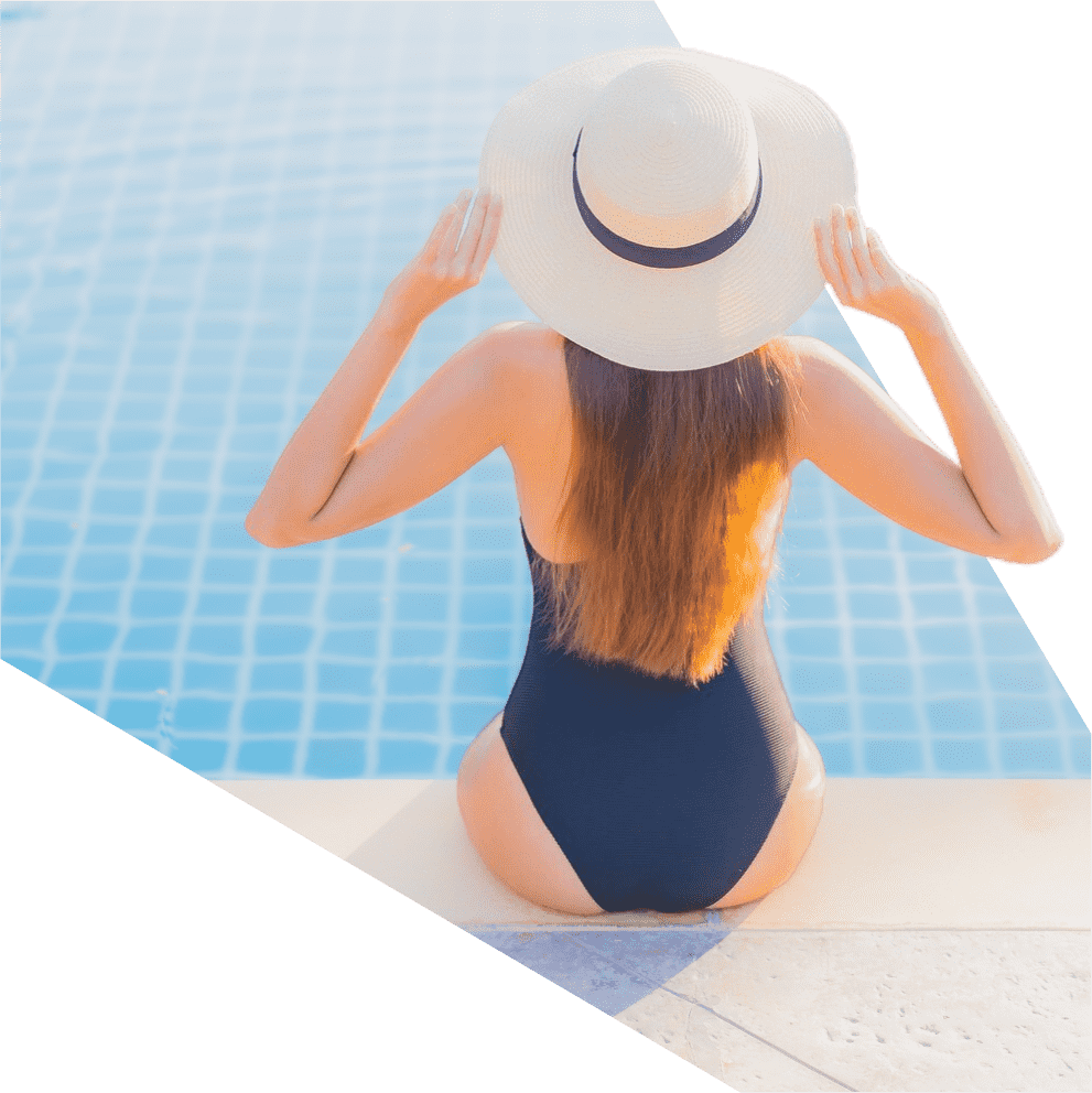 una mujer con traje de baño y sombrero está sentada junto a una piscina