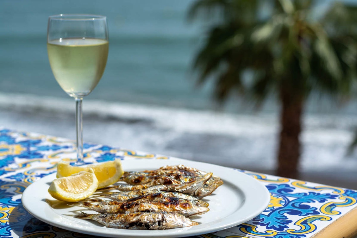 White wine and grilled fish pairing, by the sea with a palm tree.