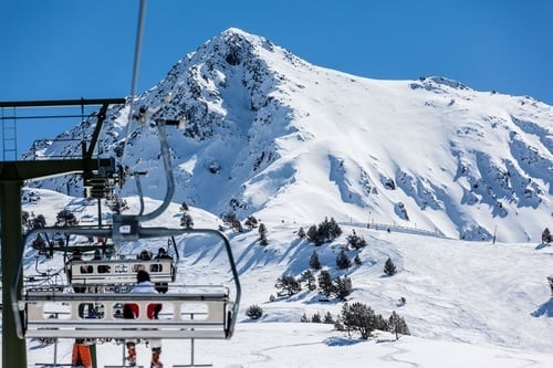 skieurs sur un téléski avec une montagne enneigée en arrière-plan