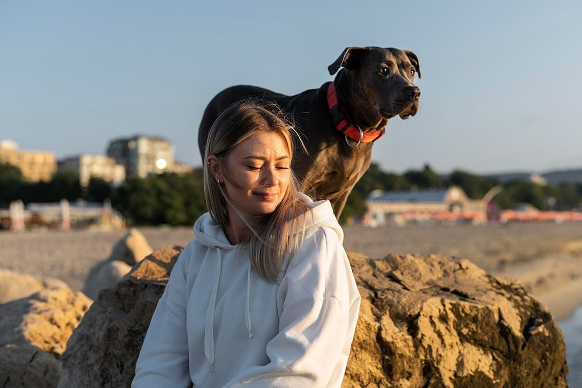 une femme assise sur un rocher avec un chien dessus