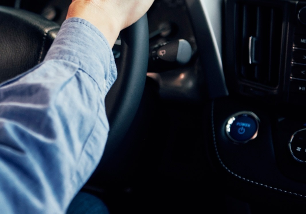 a person driving a car with a power button on the dashboard