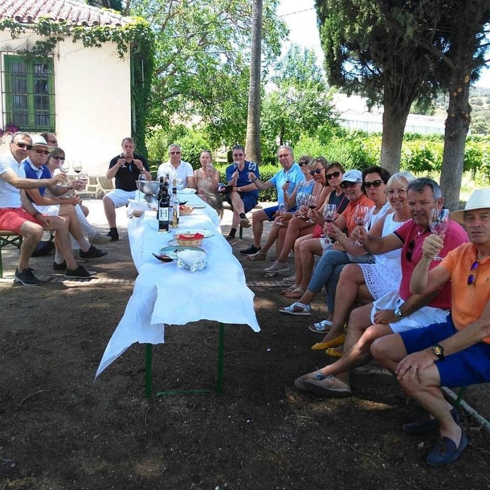 a group of people sitting around a long table drinking wine