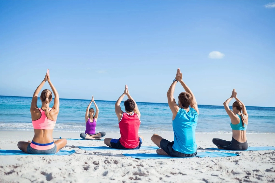 Grupo haciendo yoga en la playa frente al mar
