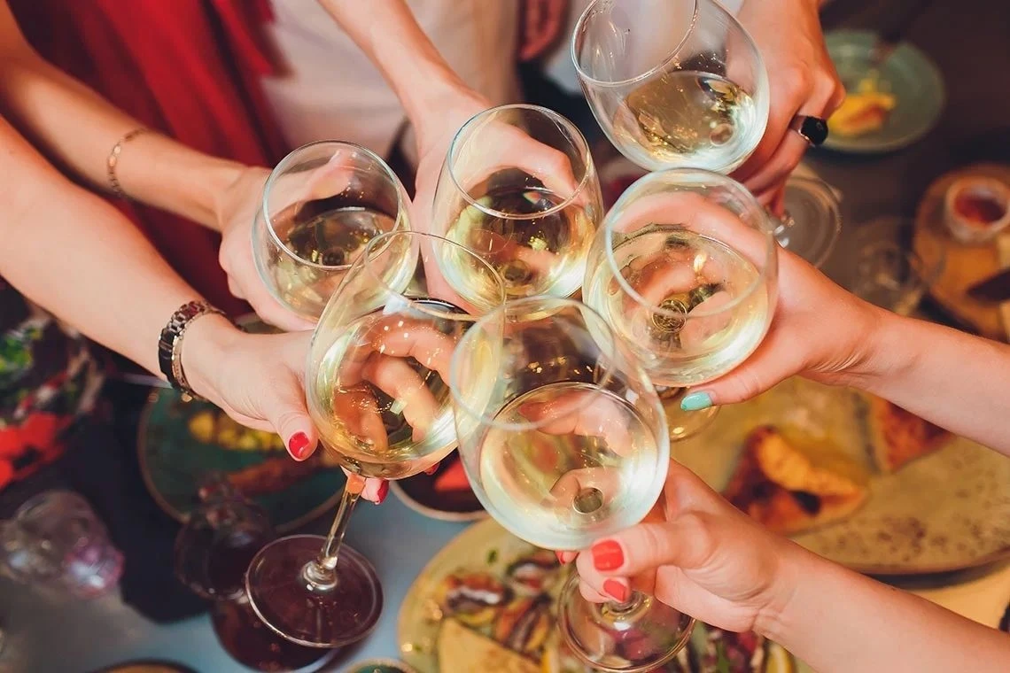 Grupo brindando con copas de vino durante una comida
