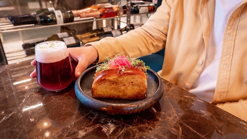 a person holding a glass of wine next to a plate of food