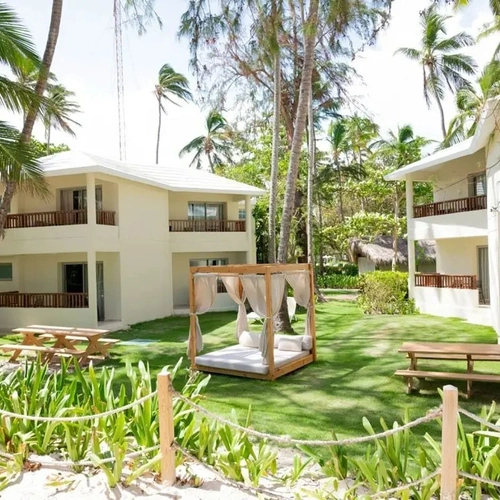 Jardín con cama balinesa entre los edificios de habitaciones de Impressive Premium Punta Cana