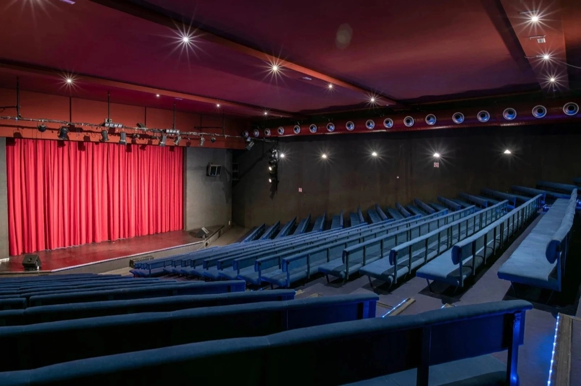 Auditorio con butacas y escenario con telón rojo