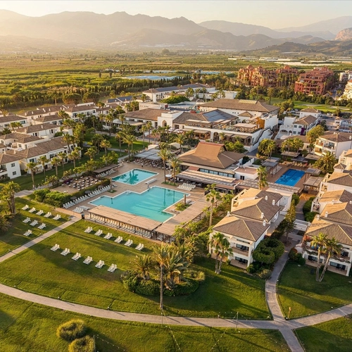 Vista aérea de Impressive Playa Granada Golf al atardecer con sus piscinas y jardines