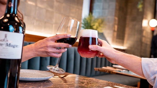 un hombre y una mujer brindan con copas de vino en un restaurante