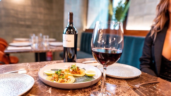 un plato de tacos y un vaso de vino en una mesa