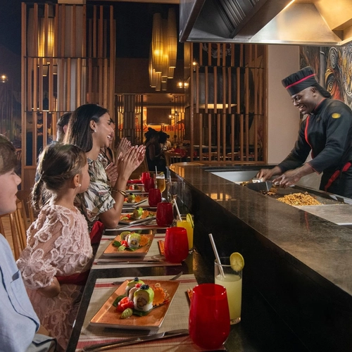 Cocinero preparando platos ante una familia en un restaurante a la carta