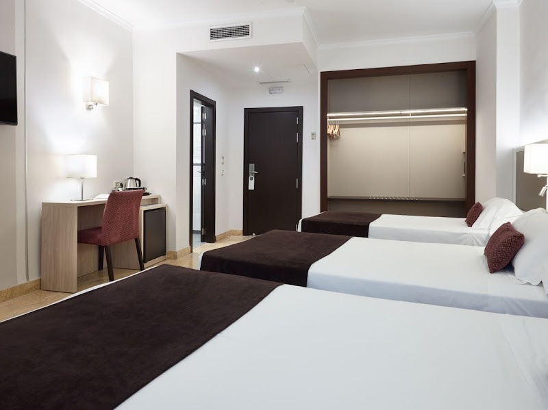 una habitación de hotel con tres camas y un escritorio