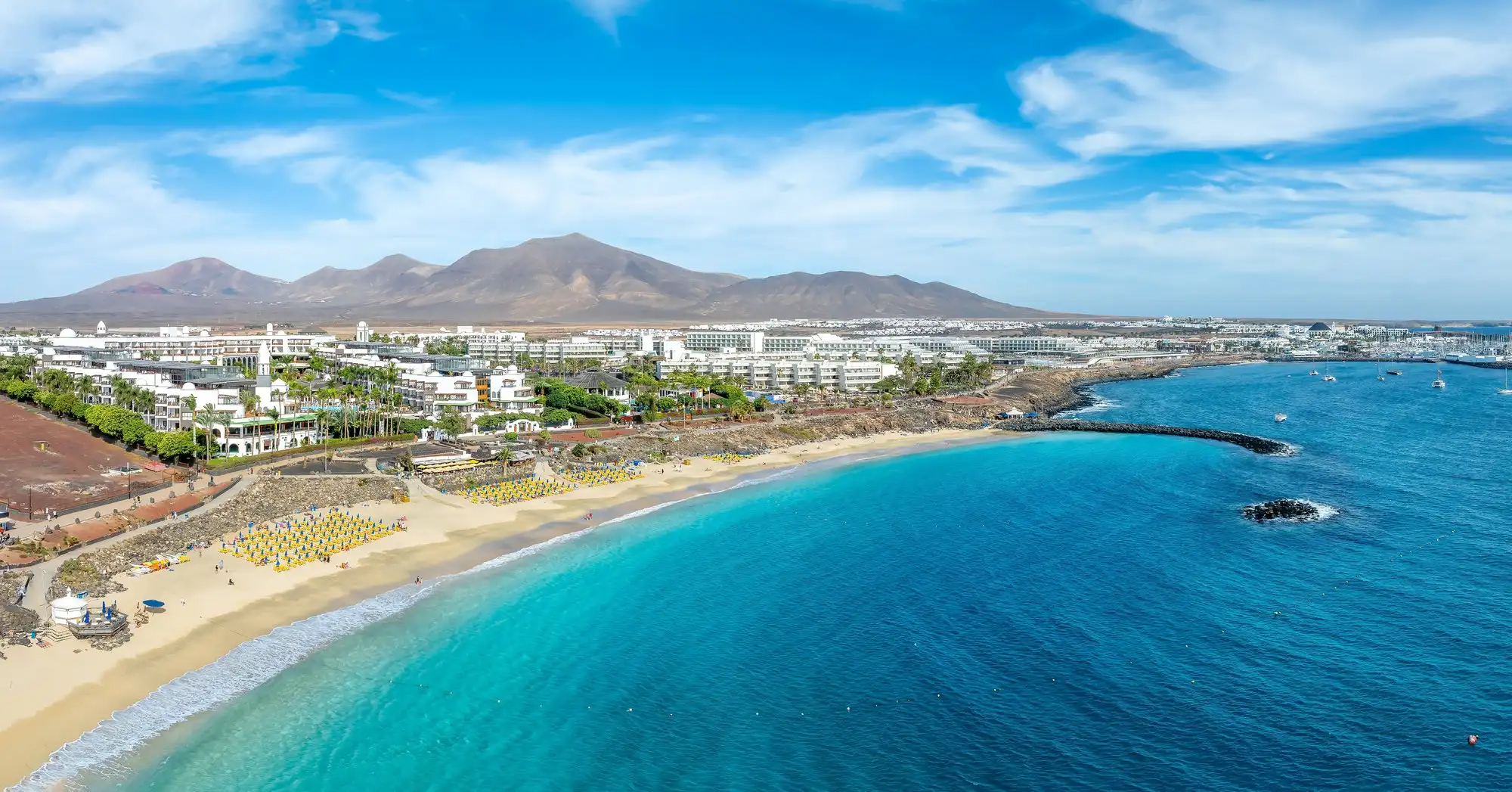 Vista aérea da Costa Teguise com a praia e os vulcões ao fundo