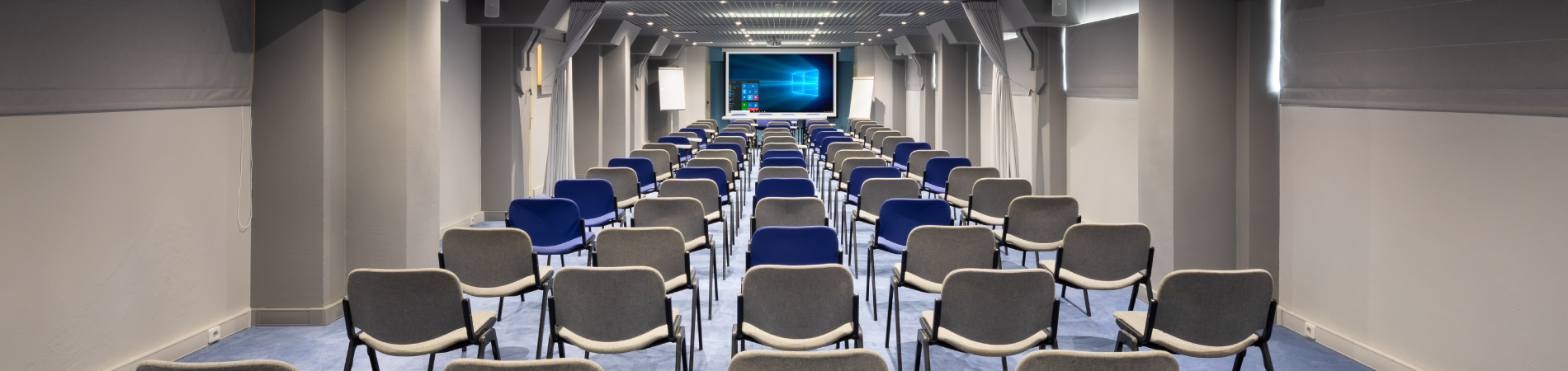 een lange gang met stoelen en een projectiescherm