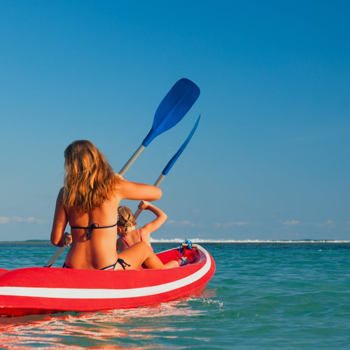 Madre e hija en un kayak en el mar turquesa