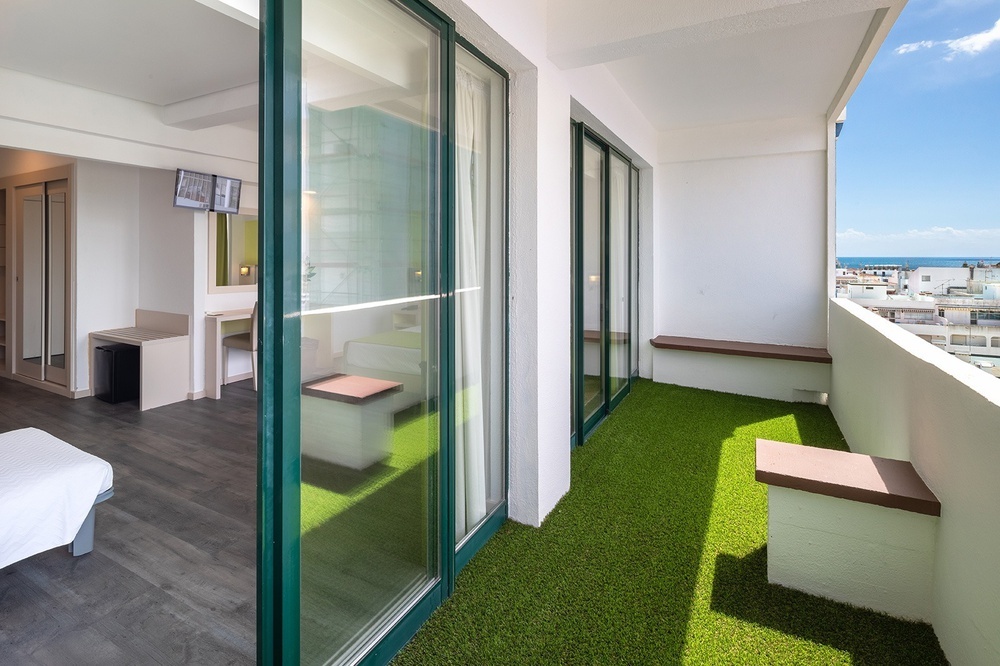 een hotelkamer met een balkon met groen gras