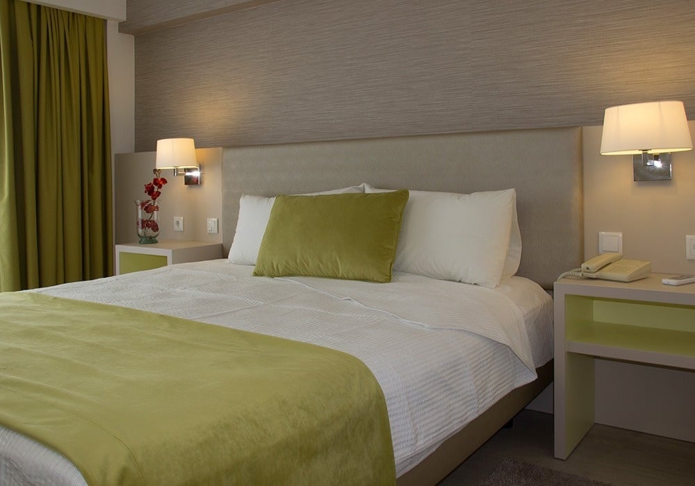 a hotel room with a green pillow on the bed